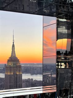 the empire building in new york city is reflected in its glass facade at sunset or dawn