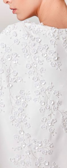 the back of a woman's wedding dress with flowers on it and beading