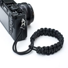 a camera with a black rope attached to it's body and the strap around it