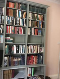 a bookshelf filled with lots of books next to a wall mounted computer monitor