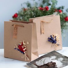 two brown bags with flowers on them are sitting on a table next to some red, white and blue flowers