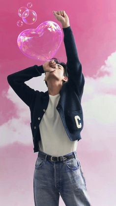 a man blowing bubbles into the air with his head in the air and holding up a heart shaped bubble