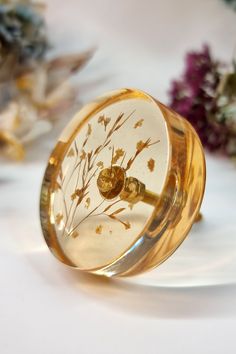 a glass ring with flowers on it sitting on top of a white table next to purple flowers