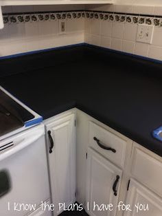 a kitchen with black counter tops and white cabinets