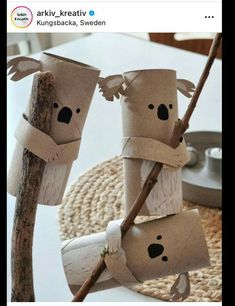 some toilet paper roll koalas are hanging on a tree branch and one is holding a twig