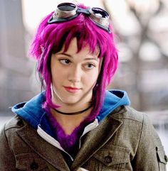 a woman with pink hair and goggles on her head