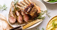 a white plate topped with meat covered in sauce and garnished with fresh herbs