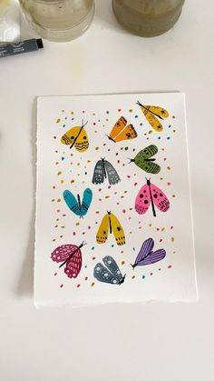 a white table topped with two jars filled with liquid and butterflies on top of it