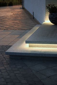 two planters sitting on top of cement steps next to a building with lights around them