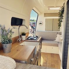 a kitchen and living area inside an rv with wood flooring, white walls and windows