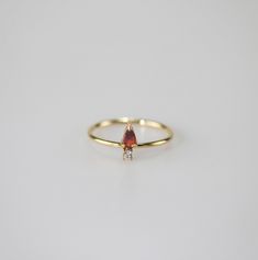 A timeless blend of elegance and versatility. Crafted with a stunning pear-shaped garnet gemstone and cute white little AAA cubic zircon. Wear it solo for understated chic or stack it up for a personalized statement. Embrace timeless beauty with our Garnet Pear Stacker Ring! 18k gold plated Stainless steel based Waterproof and tarnish free Available in US size 6-8 Ring sizing chart Elegant Teardrop Rings With Gemstone Accents, Elegant Teardrop Ring With Gemstone Accents, Elegant Teardrop Birthstone Promise Ring, Teardrop Ruby Ring For Anniversary, Elegant Teardrop Birthstone Ring As Gift, Elegant Teardrop Birthstone Ring For Gift, Elegant Teardrop Birthstone Ring, Classic Teardrop Ruby Ring For Gift, Pear-shaped Birthstone Ring For Gift