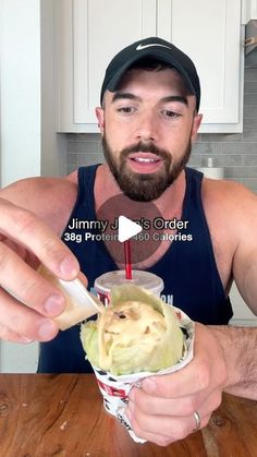 a man is eating an ice cream sundae with a straw in his hand and looking at the camera