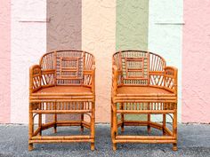 two wooden chairs sitting next to each other in front of a wall with multicolored stripes