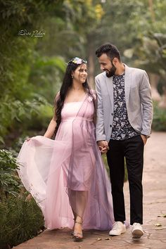 a man and woman walking down a path holding hands