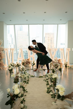 a man and woman are kissing in front of flowers