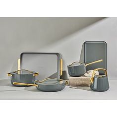 an assortment of pots and pans on display in front of a white wall with gold accents