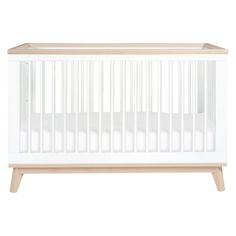 a white crib with wooden legs and no sheets on the bottom, against a white background