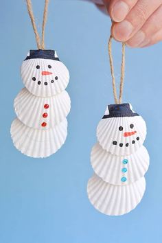 two seashells with snowmen on them hanging from twine