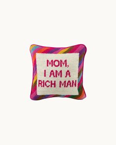 a colorful pillow with the words mom i am a rich man embroidered on it's side