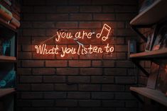 a neon sign that reads, you are d what you listen to on a brick wall