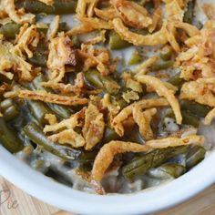 green bean casserole with onion rings in a white bowl on a wooden table