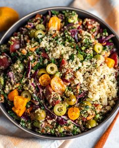 a bowl filled with rice and vegetables on top of a table next to an orange