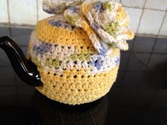 a crocheted tea pot cover with a flower on top