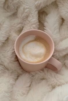 a cup of coffee sitting on top of a fluffy white blanket