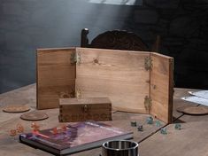 an open wooden box sitting on top of a table next to dice and other items