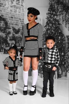 two young children standing next to each other in front of a christmas tree wearing black and white outfits