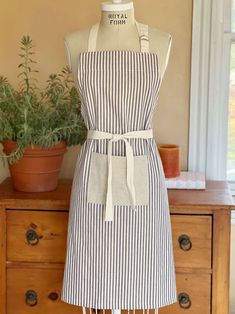 an apron on a mannequin in front of a potted plant