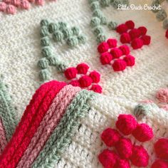 a crocheted blanket with red flowers on it