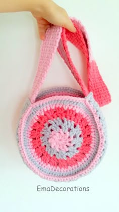 a crocheted purse being held by a woman's hand on a white surface