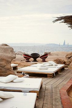 two lounge chairs sitting on top of a wooden deck next to the ocean