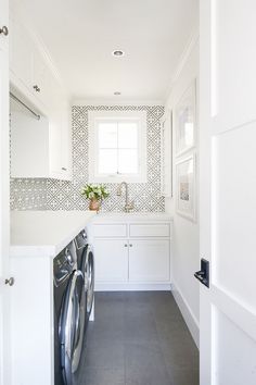 a washer and dryer in a white laundry room with tile wallpaper on the walls