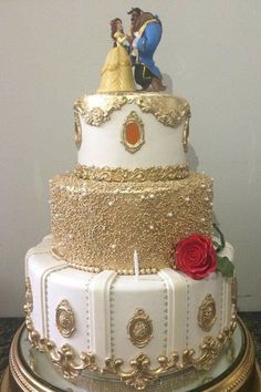 a white and gold wedding cake with figurines on top