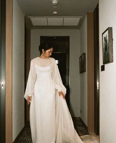 a woman in a white dress walking down a hallway