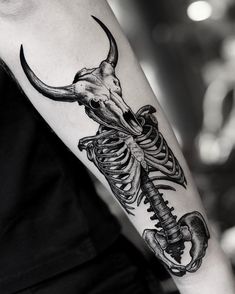 a man's arm with a skeleton and an animal skull on it, in black and white