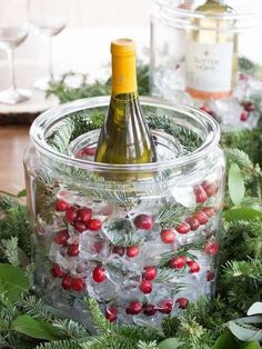 a bottle of wine sitting inside of a glass container filled with ice and cranberries