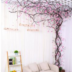 the living room is decorated with pink flowers and branches on the wall, along with bookshelves