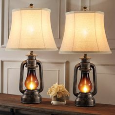 two lamps sitting on top of a table next to a vase with flowers in it