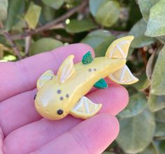 a yellow toy animal with green leaves on it's head sitting in a person's hand