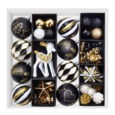 an assortment of black and gold christmas ornaments in a display box with white trimmings