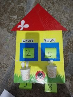 a paper house made to look like it has numbers on the front and two cups with toothpicks in them