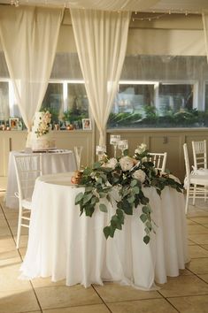 a table with flowers and greenery is set up for a wedding reception in the sun