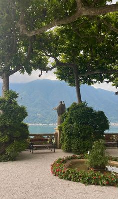 the statue is surrounded by trees and flowers