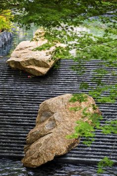 two large rocks sitting on top of a metal grate next to a river filled with water