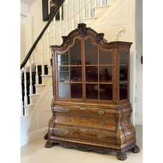 an old wooden dresser with glass doors on the front and side, next to a stair case