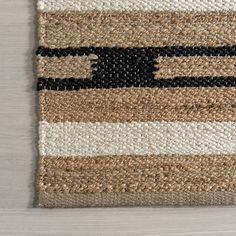 an area rug with black, white and tan stripes on top of a wooden floor