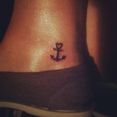 a small anchor tattoo on the side of a woman's lower back ribcage